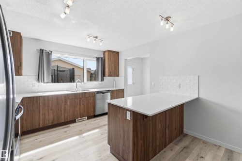 Modern kitchen featuring wood-finish cabinetry, white countertops, and a white subway tile backsplash - 22371 93 Avenue, Edmonton, AB - Indoor Photo Showing Kitchen