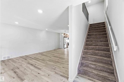 Carpeted staircase with white handrail and black metal balusters - 22371 93 Avenue, Edmonton, AB - Indoor Photo Showing Other Room