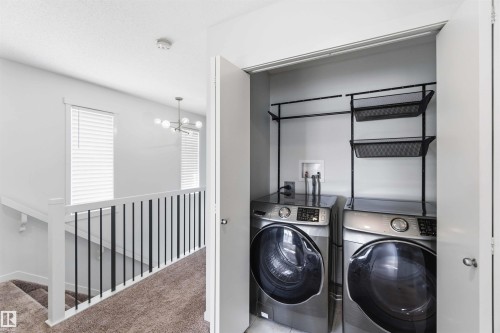 Dedicated laundry closet with front-loading appliances, integrated shelving, and a hanging rod - 22371 93 Avenue, Edmonton, AB - Indoor Photo Showing Laundry Room