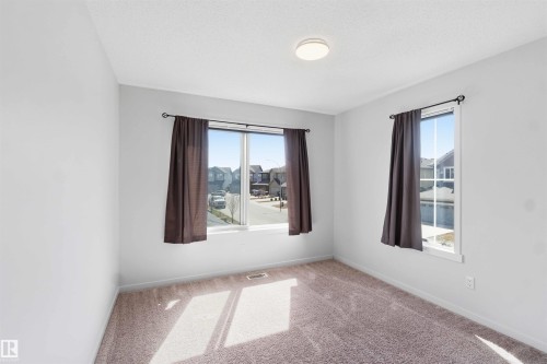 Room featuring two windows with white trim, light gray walls, and textured carpet flooring - 22371 93 Avenue, Edmonton, AB - Indoor Photo Showing Other Room