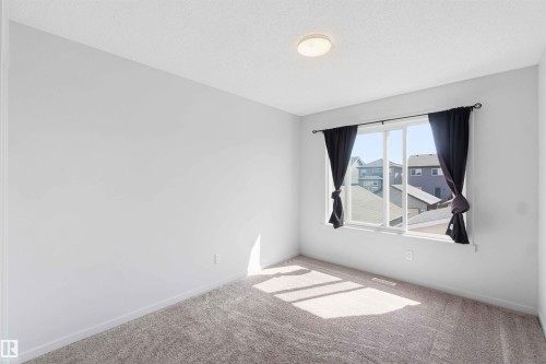 Bright room featuring a large window, neutral wall paint, and textured carpeting - 22371 93 Avenue, Edmonton, AB - Indoor Photo Showing Other Room