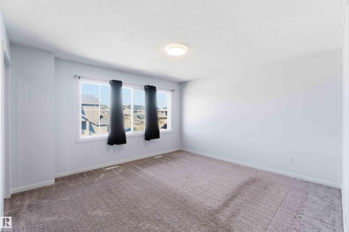 Spacious room featuring neutral carpeting, light-toned walls, and a large window providing natural illumination - 22371 93 Avenue, Edmonton, AB - Indoor Photo Showing Other Room