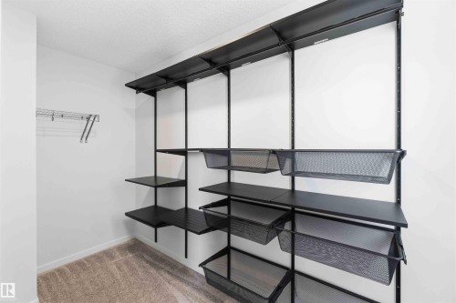 Customizable black shelving system with integrated wire baskets, alongside a chrome wire shelf and hanging rod - 22371 93 Avenue, Edmonton, AB - Indoor Photo Showing Other Room