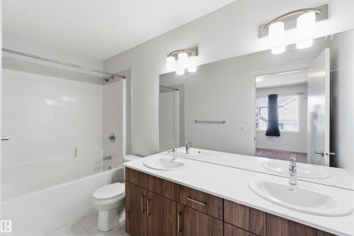 Double vanity featuring wood-finish cabinetry, white countertops, and undermount sinks - 22371 93 Avenue, Edmonton, AB - Indoor Photo Showing Bathroom