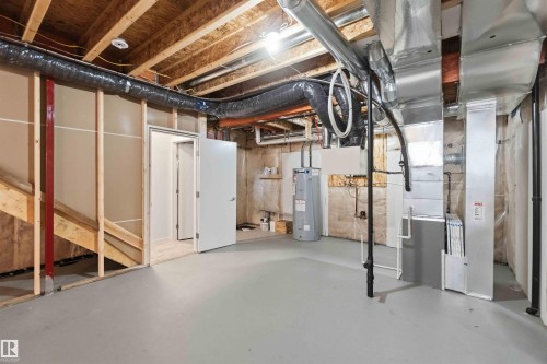 Unfinished lower level with exposed ceiling joists, painted concrete flooring, and an open doorway leading to an interior space - 22371 93 Avenue, Edmonton, AB - Indoor Photo Showing Basement