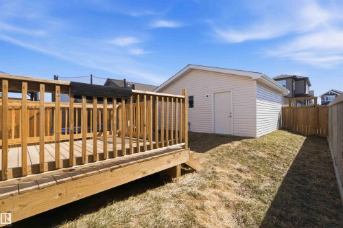 Expansive backyard featuring a wood deck, detached garage with vinyl siding, privacy fencing, and a sloped lawn - 22371 93 Avenue, Edmonton, AB - Outdoor With Exterior