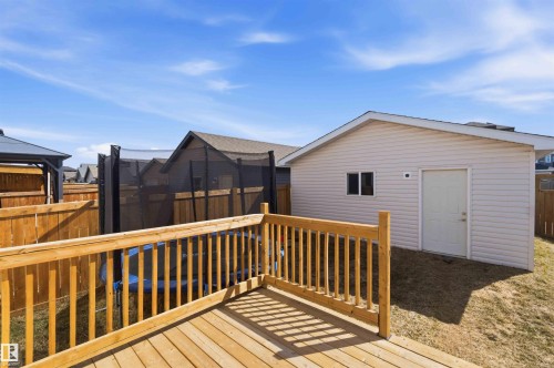 Spacious outdoor wood deck with natural wood railing, leading to a detached auxiliary building with siding and a side entry door, all within a fenced property perimeter - 22371 93 Avenue, Edmonton, AB - Outdoor With Deck Patio Veranda With Exterior