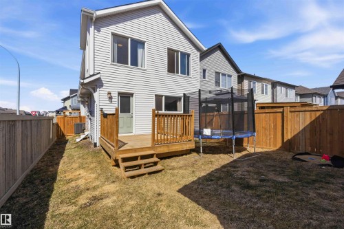 Rear exterior featuring white vinyl siding, a wooden deck with railing, and a ground-level entrance - 22371 93 Avenue, Edmonton, AB - Outdoor With Deck Patio Veranda