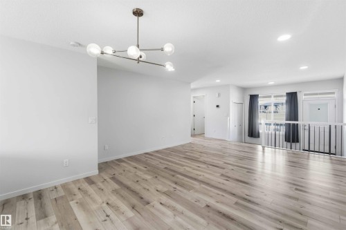 Spacious open-concept room featuring wood-finish flooring, a contemporary ceiling light fixture, recessed lighting, and crisp white walls - 22371 93 Avenue, Edmonton, AB - Indoor Photo Showing Other Room