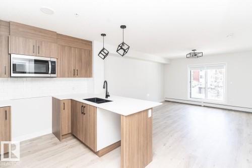 Modern kitchen featuring wood-finish cabinetry, white countertops, and a subway tile backsplash - #204 2225 44 Av Nw, Edmonton, AB - Indoor Photo Showing Kitchen