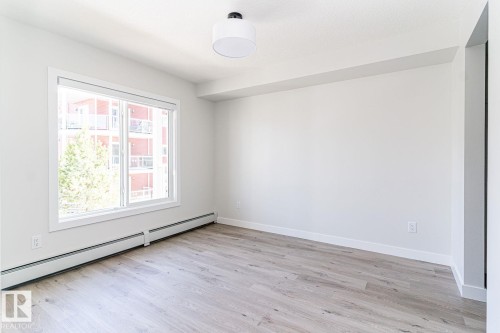 Spacious room featuring light wood-finish flooring and a large window - #204 2225 44 Av Nw, Edmonton, AB - Indoor Photo Showing Other Room