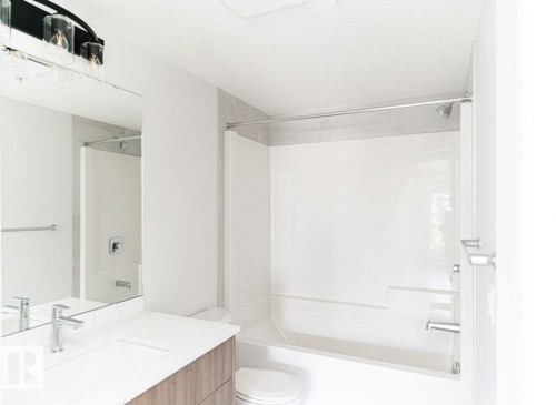 Full bathroom featuring a single vanity with wood-finish cabinetry, a built-in sink, and a chrome faucet - #204 2225 44 Av Nw, Edmonton, AB - Indoor Photo Showing Bathroom