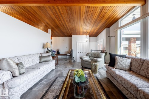 Vaulted wood-paneled ceiling with exposed wood beams, large picture window, and gray tile flooring - 16536 103 Street, Edmonton, AB - Indoor Photo Showing Living Room