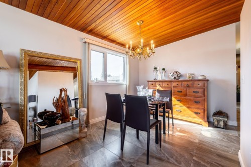 Vaulted wood-paneled ceiling with a brass chandelier, large window, and stone-finish tile flooring - 16536 103 Street, Edmonton, AB - Indoor Photo Showing Dining Room