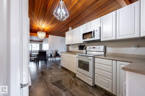 Kitchen featuring white cabinetry, stone-finish countertops, and built-in appliances - 16536 103 Street, Edmonton, AB - Indoor Photo Showing Kitchen