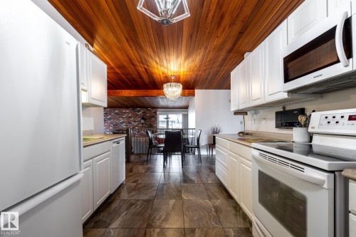 Kitchen featuring white cabinetry, white appliances, a wood-paneled ceiling, and tiled flooring - 16536 103 Street, Edmonton, AB - Indoor Photo Showing Kitchen