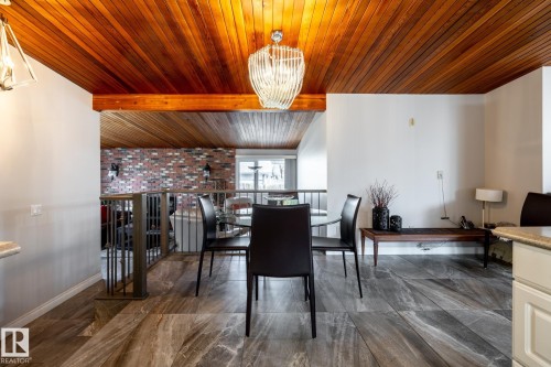 Dining area featuring a wood-panel ceiling, contemporary chandelier, and large format tile flooring - 16536 103 Street, Edmonton, AB - Indoor Photo Showing Dining Room