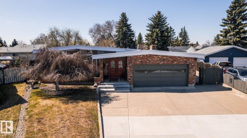Brick facade residence with a prominent two-car garage featuring a dark gray door - 16536 103 Street, Edmonton, AB - Outdoor
