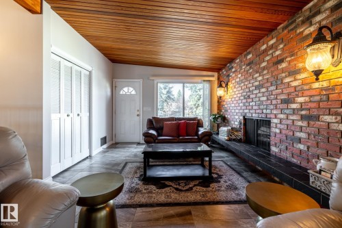 Exposed brick accent wall with a built-in fireplace and dark hearth - 16536 103 Street, Edmonton, AB - Indoor Photo Showing Living Room With Fireplace