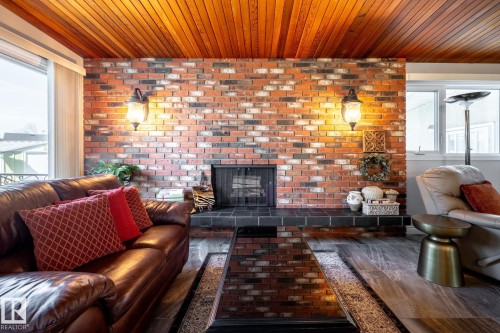 Exposed brick fireplace with a black tile hearth and two wall-mounted sconces - 16536 103 Street, Edmonton, AB - Indoor Photo Showing Living Room With Fireplace