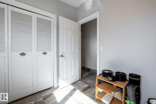 Louvered bifold doors with decorative hardware, paneled interior door, and gray-toned tile flooring - 16536 103 Street, Edmonton, AB - Indoor Photo Showing Other Room