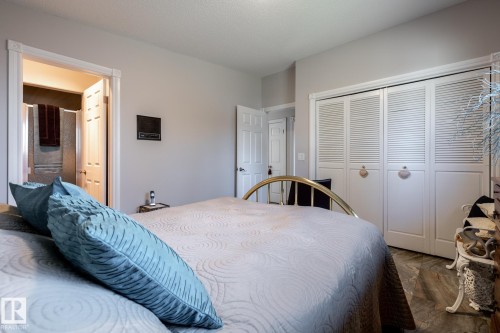Bedroom featuring louvered bi-fold closet doors, wood-finish flooring, and light gray wall tones - 16536 103 Street, Edmonton, AB - Indoor Photo Showing Bedroom