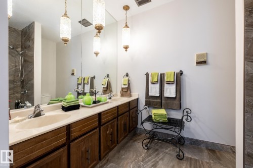 Bathroom featuring a double vanity with integrated sinks, wood-finish cabinetry, and a full-width mirror - 16536 103 Street, Edmonton, AB - Indoor Photo Showing Bathroom