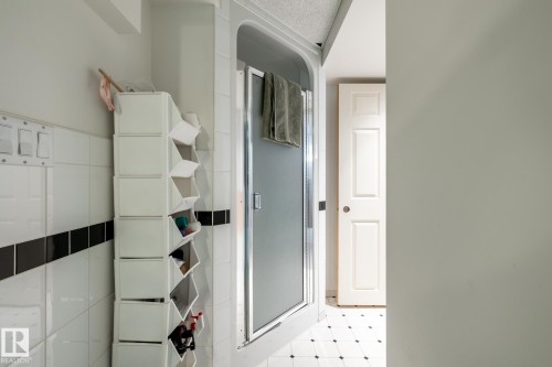 Enclosed shower with frosted glass, white wall tiles with a black accent band, and a white six-panel door - 16536 103 Street, Edmonton, AB - Indoor