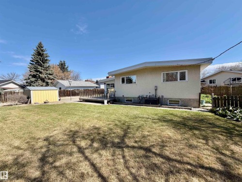 Expansive backyard featuring a large lawn area, a spacious wooden deck, and a detached storage shed - 16536 103 Street, Edmonton, AB - Outdoor With Exterior