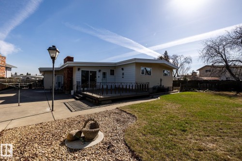 Rear exterior with a spacious concrete patio, private deck, and brick chimney accents - 16536 103 Street, Edmonton, AB - Outdoor With Deck Patio Veranda