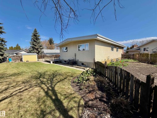 Expansive lawn space featuring a wooden deck, a detached storage shed, mature perimeter trees, and a partial wooden fence - 16536 103 Street, Edmonton, AB - Outdoor