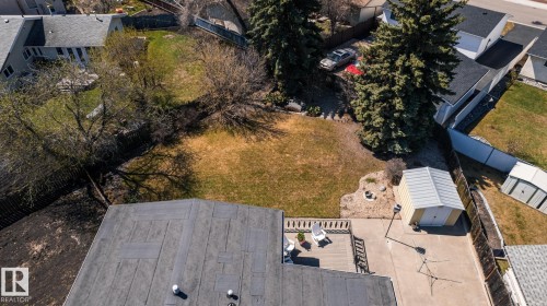 Expansive backyard featuring a manicured lawn, established trees, and a concrete patio with perimeter fencing - 16536 103 Street, Edmonton, AB - Outdoor