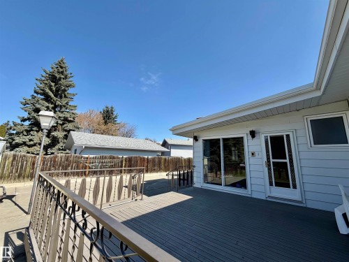 Spacious outdoor deck with dark composite decking, offering direct access to the interior via a sliding glass door and an additional entry door - 16536 103 Street, Edmonton, AB - Outdoor With Deck Patio Veranda With Exterior