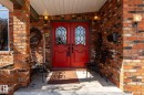 Brick exterior featuring a red double-door entry with decorative glass inserts, concrete porch, and exterior sconce lighting - 16536 103 Street, Edmonton, AB  - Outdoor 