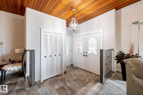 Entryway featuring a wood-panel ceiling, double entry doors with decorative glass, and large format tile flooring - 16536 103 Street, Edmonton, AB - Indoor Photo Showing Other Room