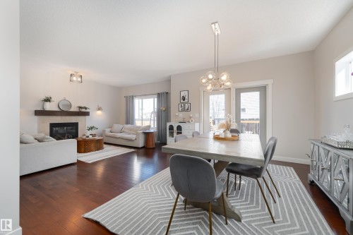 Open-concept living and dining areas featuring dark wood-finish flooring, a contemporary fireplace with a wood mantle, and bright natural light - 22064 95 Avenue, Edmonton, AB - Indoor With Fireplace