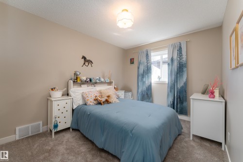 Neutral-toned room featuring a window with white trim, soft gray carpeting, a built-in wall vent, and a flush-mount ceiling light fixture - 22064 95 Avenue, Edmonton, AB - Indoor Photo Showing Bedroom