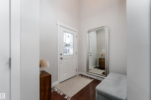 Entryway featuring a white paneled door with decorative glass inserts, dark wood-finish flooring, and light neutral wall paint - 22064 95 Avenue, Edmonton, AB - Indoor Photo Showing Other Room
