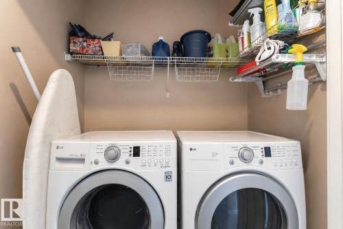 Dedicated laundry area featuring front-loading appliances, overhead wire shelving, and wall-mounted drying rods - 22064 95 Avenue, Edmonton, AB - Indoor Photo Showing Laundry Room