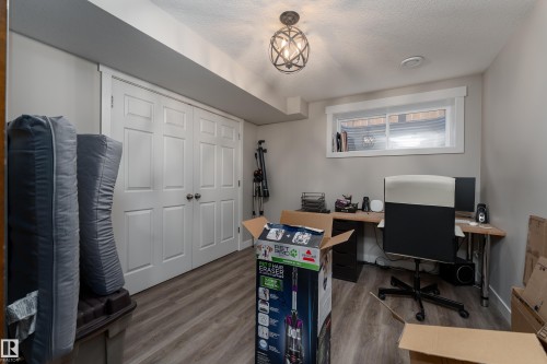 Room featuring wood-finish flooring, a window with white trim, a built-in closet with bi-fold doors, a desk area, and a semi-flush mount light fixture - 22064 95 Avenue, Edmonton, AB - Indoor Photo Showing Office