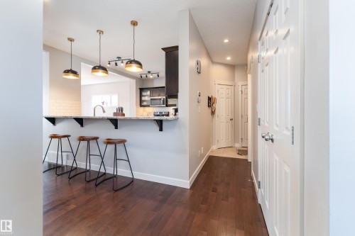 Kitchen peninsula with a light-toned countertop, subway tile backsplash, and dark wood-finish flooring - 22064 95 Avenue, Edmonton, AB - Indoor