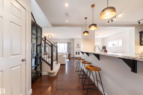 Spacious kitchen island featuring a light-toned countertop and three pendant lights - 22064 95 Avenue, Edmonton, AB - Indoor Photo Showing Other Room
