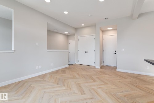 Open-concept interior featuring light wood-finish herringbone flooring, recessed lighting, and white baseboards - 44 16231 19 Avenue, Edmonton, AB - Indoor Photo Showing Other Room