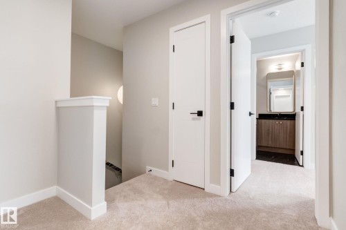 Hallway featuring light-toned carpeting, white trim, and doors with matte black hardware - 44 16231 19 Avenue, Edmonton, AB - Indoor Photo Showing Other Room
