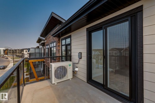Private balcony with concrete flooring, black-framed sliding glass doors, and a glass panel railing - 44 16231 19 Avenue, Edmonton, AB - Outdoor With Balcony With Exterior