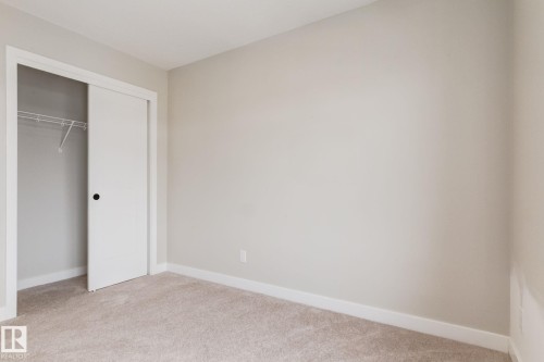 Bedroom featuring neutral wall paint, carpet flooring, white baseboards, and a bi-fold closet with wire shelving - 44 16231 19 Avenue, Edmonton, AB - Indoor Photo Showing Other Room