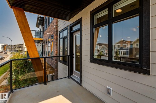 Exterior balcony featuring a concrete floor, glass and metal railing, and a wood-finish structural beam - 44 16231 19 Avenue, Edmonton, AB - Outdoor With Balcony With Exterior