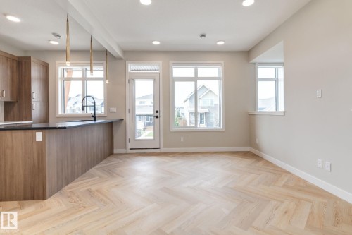 Open-concept living area featuring light wood-finish flooring with a herringbone pattern - 44 16231 19 Avenue, Edmonton, AB - Indoor Photo Showing Kitchen