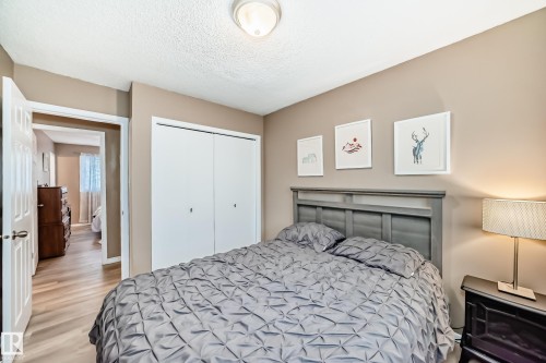 This bedroom features neutral-toned walls, light wood-look flooring, and a ceiling light fixture - 9813 152 Street, Edmonton, AB - Indoor Photo Showing Bedroom