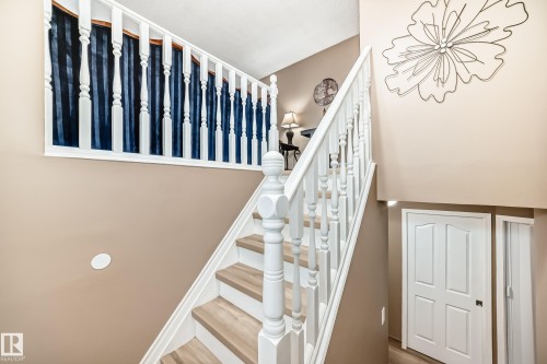 The property features a staircase with white spindles and light wood treads, complemented by a white handrail - 9813 152 Street, Edmonton, AB - Indoor Photo Showing Other Room
